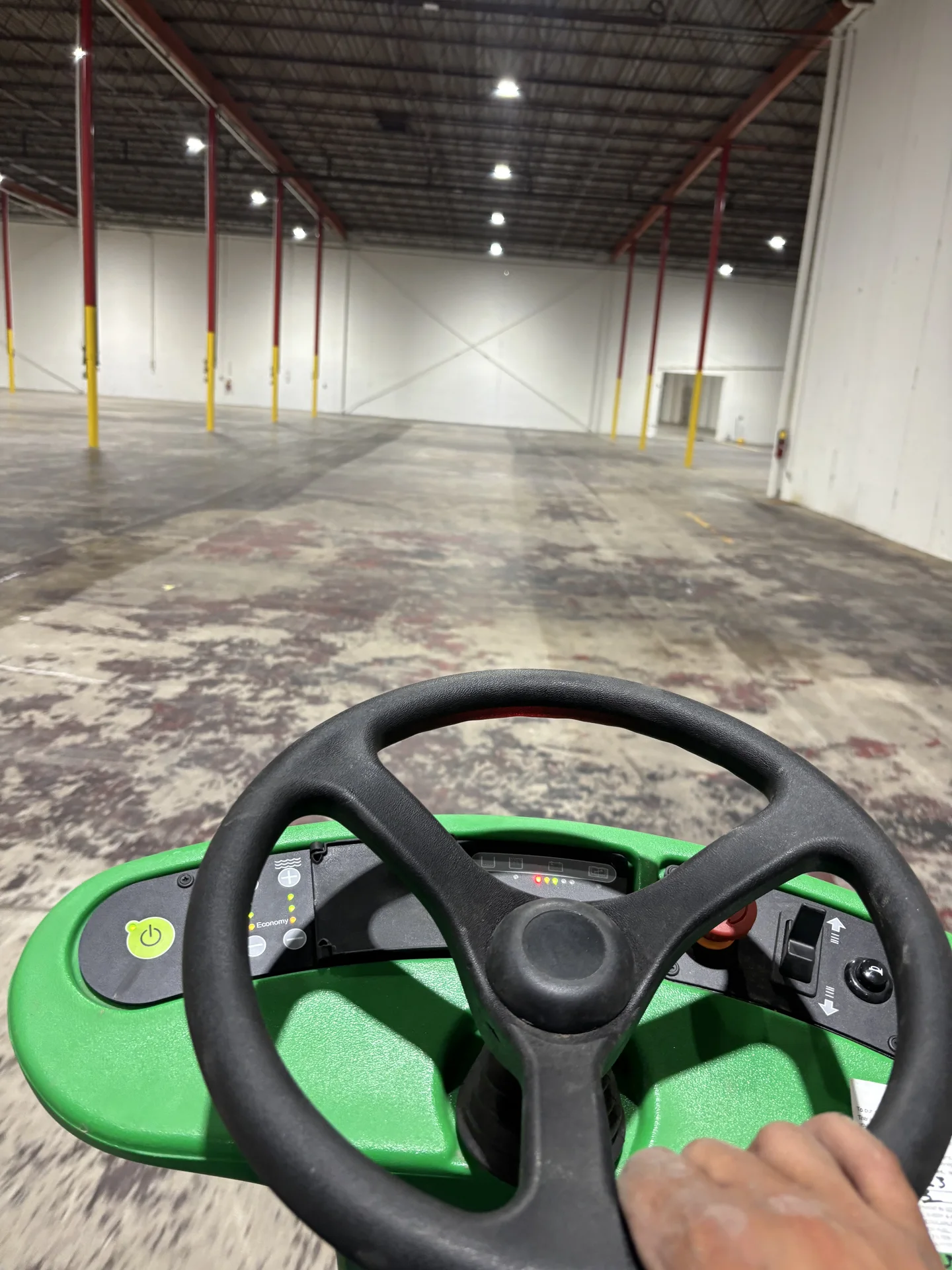 Ride-on floor scrubber during commercial and industrial warehouse floor cleaning
