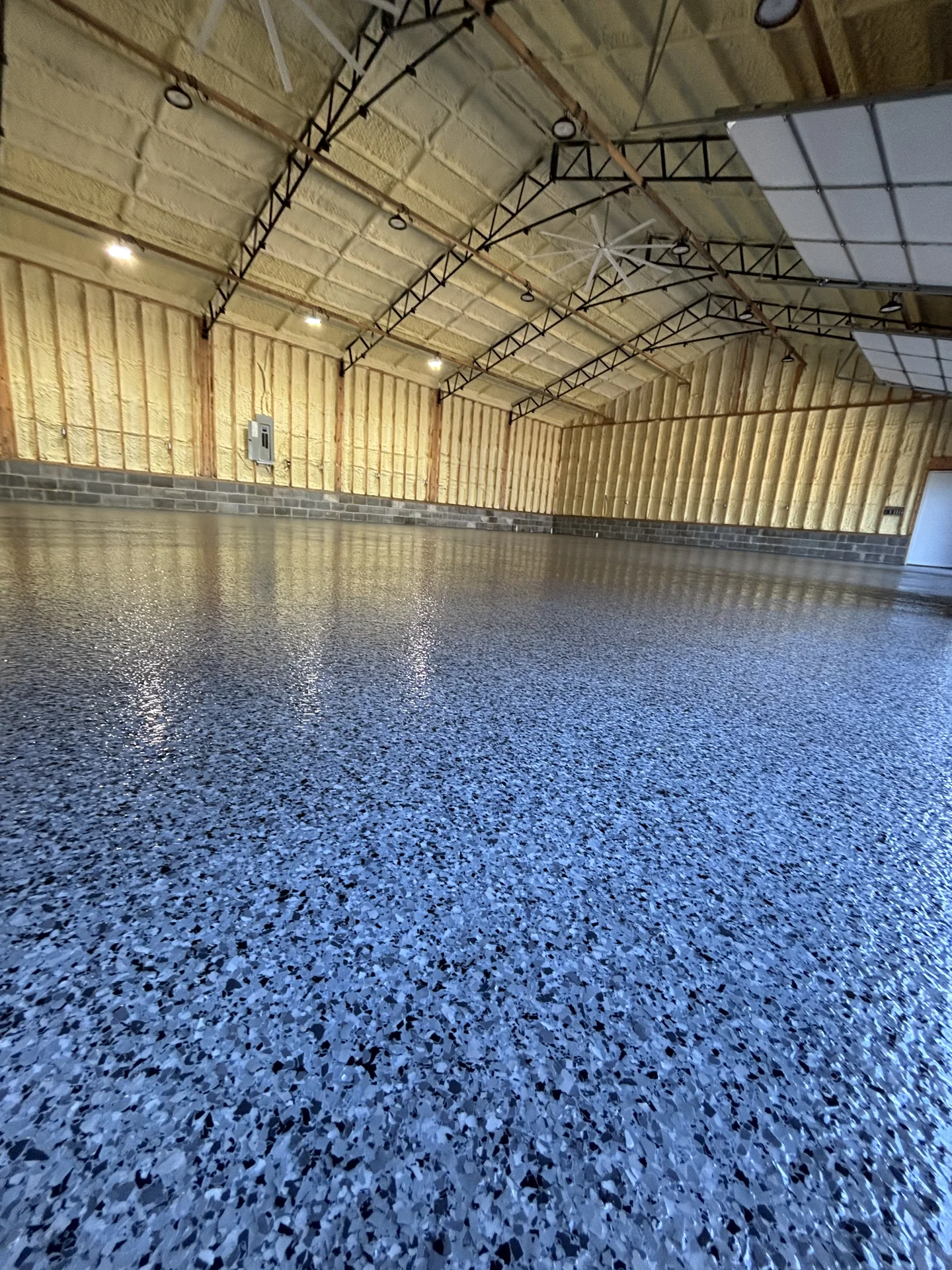 Wide view of a blue flake epoxy floor in a residential metal building