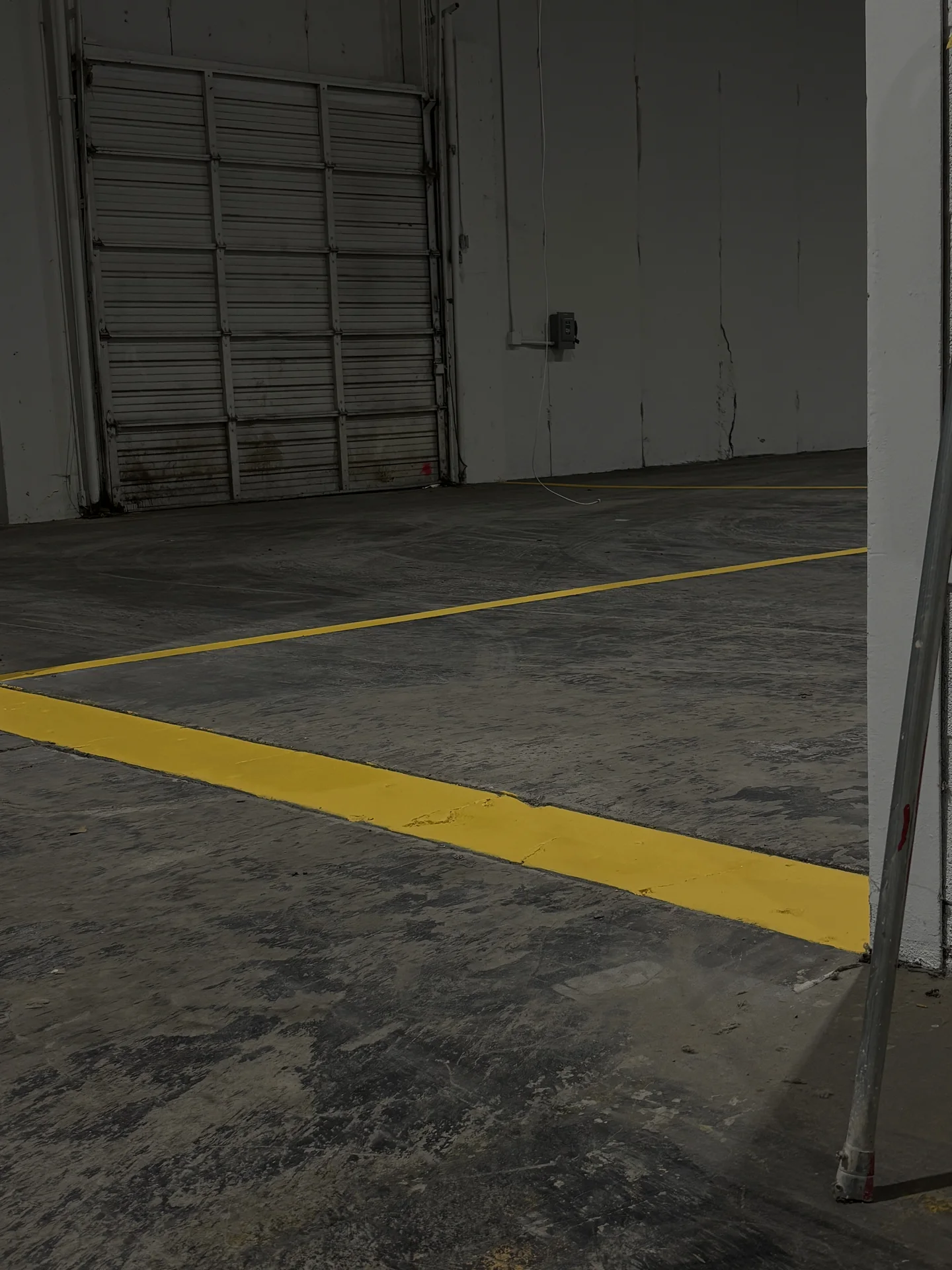 Yellow floor striping beside an industrial roll-up door