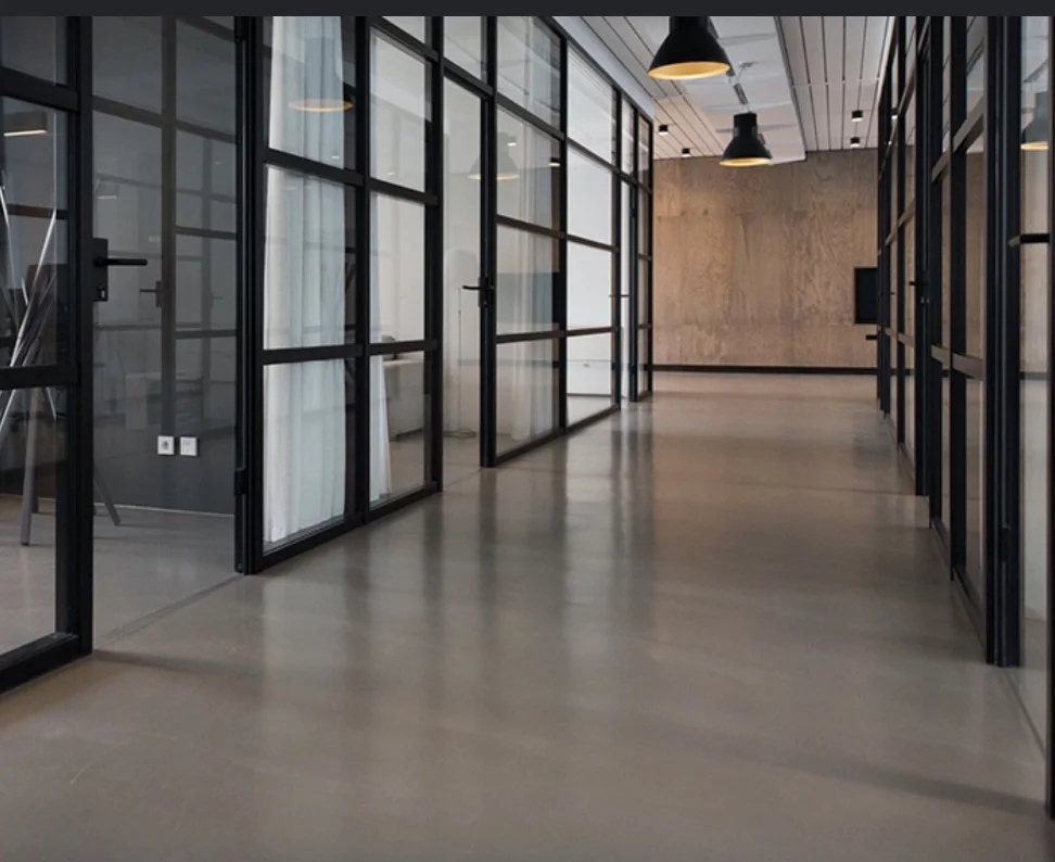 Polished concrete corridor beside glass office partitions