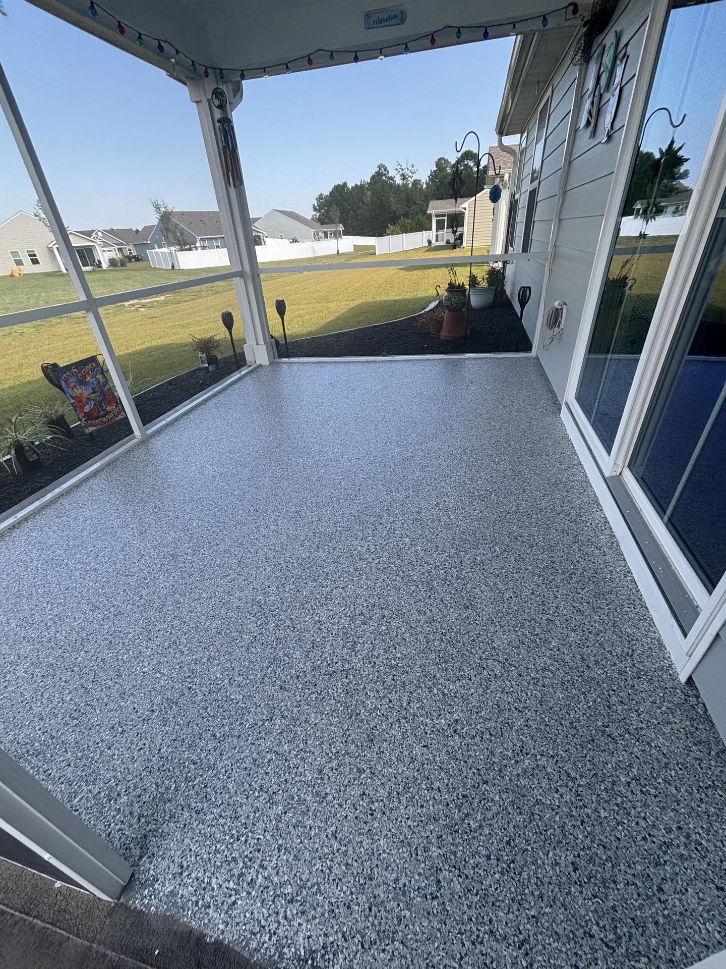 Coated outdoor residential concrete beside a screened porch